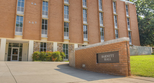 Brick building with a brick sign at the front entrance saying "Barnett Hall"