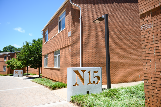Exterior view of Calhoun Courts, a  two story brick residence hall with a central entrance, large windows, and a landscaped courtyard.