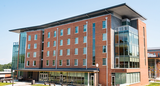 Exterior view of Gressette Hall, a multi-story brick residence hall with a central entrance and large windows.