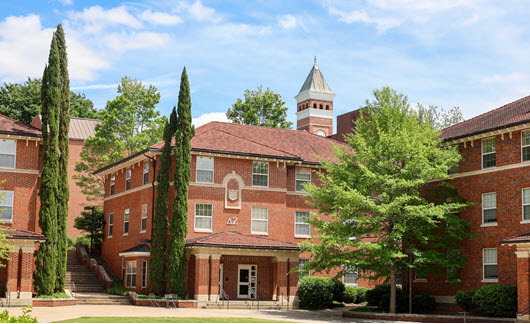 Exterior view of Simpson Hall, a multi-story brick residence hall with a central entrance, large windows, and a landscaped courtyard.