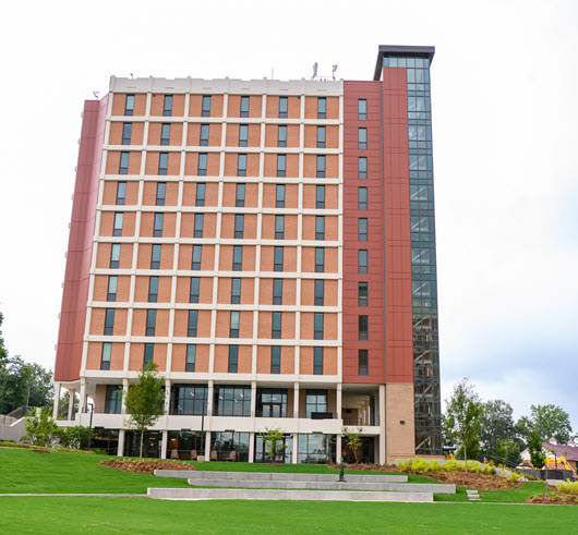 Exterior view of Byrnes Hall, a multi-story brick residence hall with large windows.