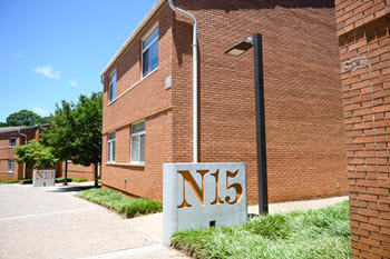 Exterior view of Calhoun Courts, a  two story brick residence hall with a central entrance, large windows, and a landscaped courtyard.