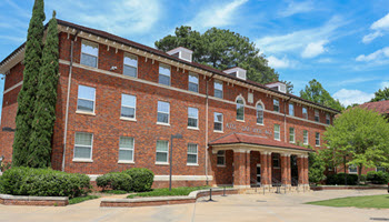 Exterior view of Donaldson Hall, a multi-story brick residence hall with a central entrance, large windows, and a landscaped courtyard.