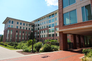 Exterior view of Douthit Hills B, a multi-story brick residence hall with a central entrance, large windows, and a landscaped courtyard.