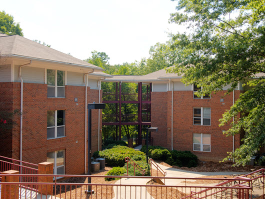 Exterior view of Lightsey Bridge I, a multi-story residence building with open-air walkways, stair access, and surrounding greenery.