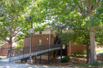 Exterior view of Lightsey Bridge II, a multi-story residence building with open-air walkways, stair access, and surrounding greenery.