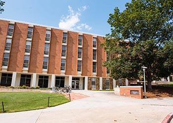 Exterior view of Mauldin Hall, a multi-story brick residence hall with a central entrance, large windows, and a landscaped courtyard.