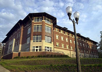 Exterior view of Mickel Hall, a multi-story brick residence hall with a central entrance, large windows, and a landscaped courtyard.