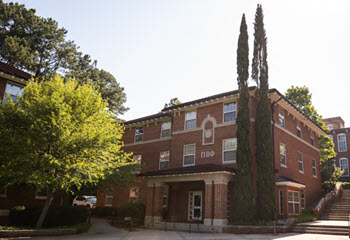 Exterior view of Simpson North Hall, a multi-story brick residence hall with a central entrance, large windows, and a landscaped courtyard.