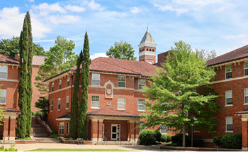 Exterior view of Simpson South Hall, a multi-story brick residence hall with a central entrance, large windows, and a landscaped courtyard.