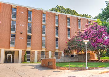 Exterior view of Smith Hall, a multi-story brick residence hall with a central entrance, large windows, and a landscaped courtyard.